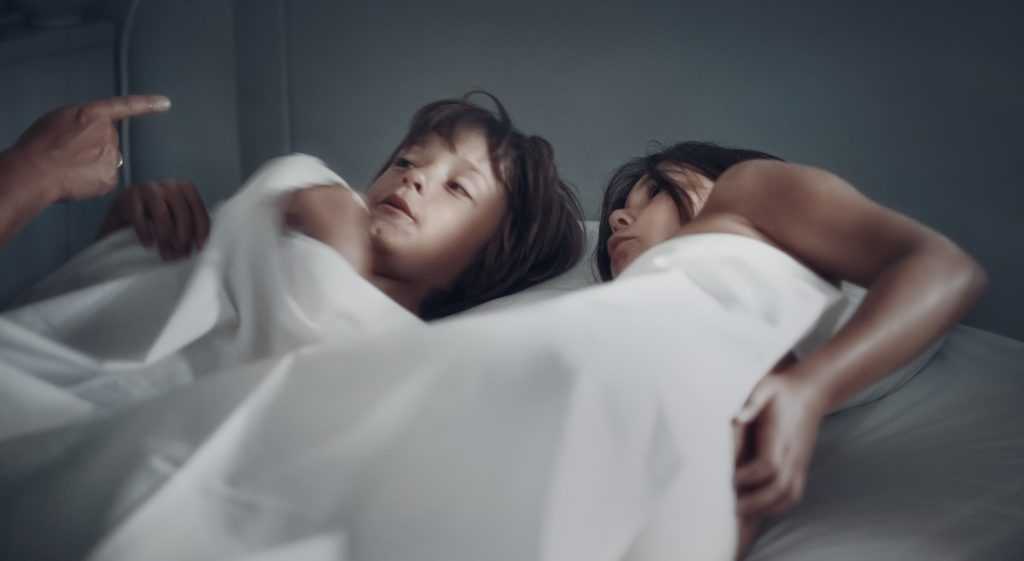 young child lying in bed with mother