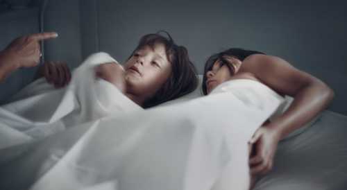 young child lying in bed with mother