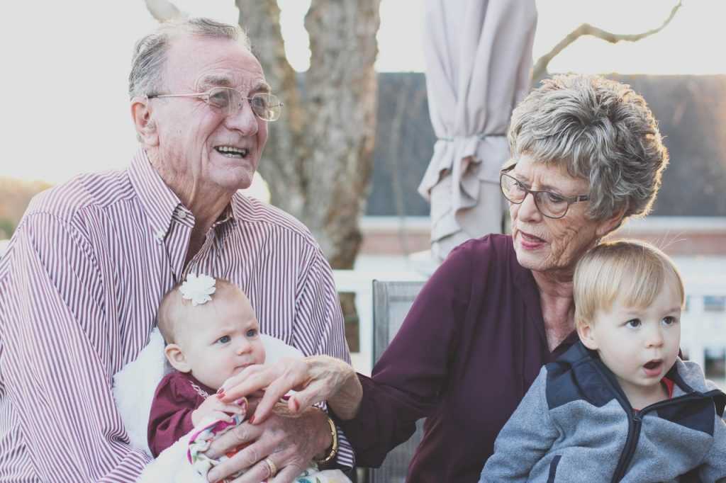 elderly couple holding two young children