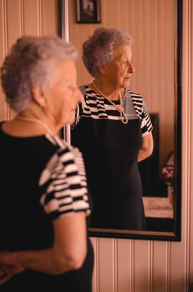 elderly woman looking into a mirror
