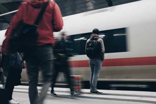 man standing on train platform with training going by