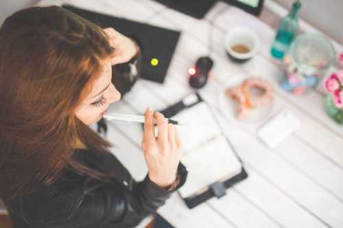 woman sitting at a desk with pen in her mouth